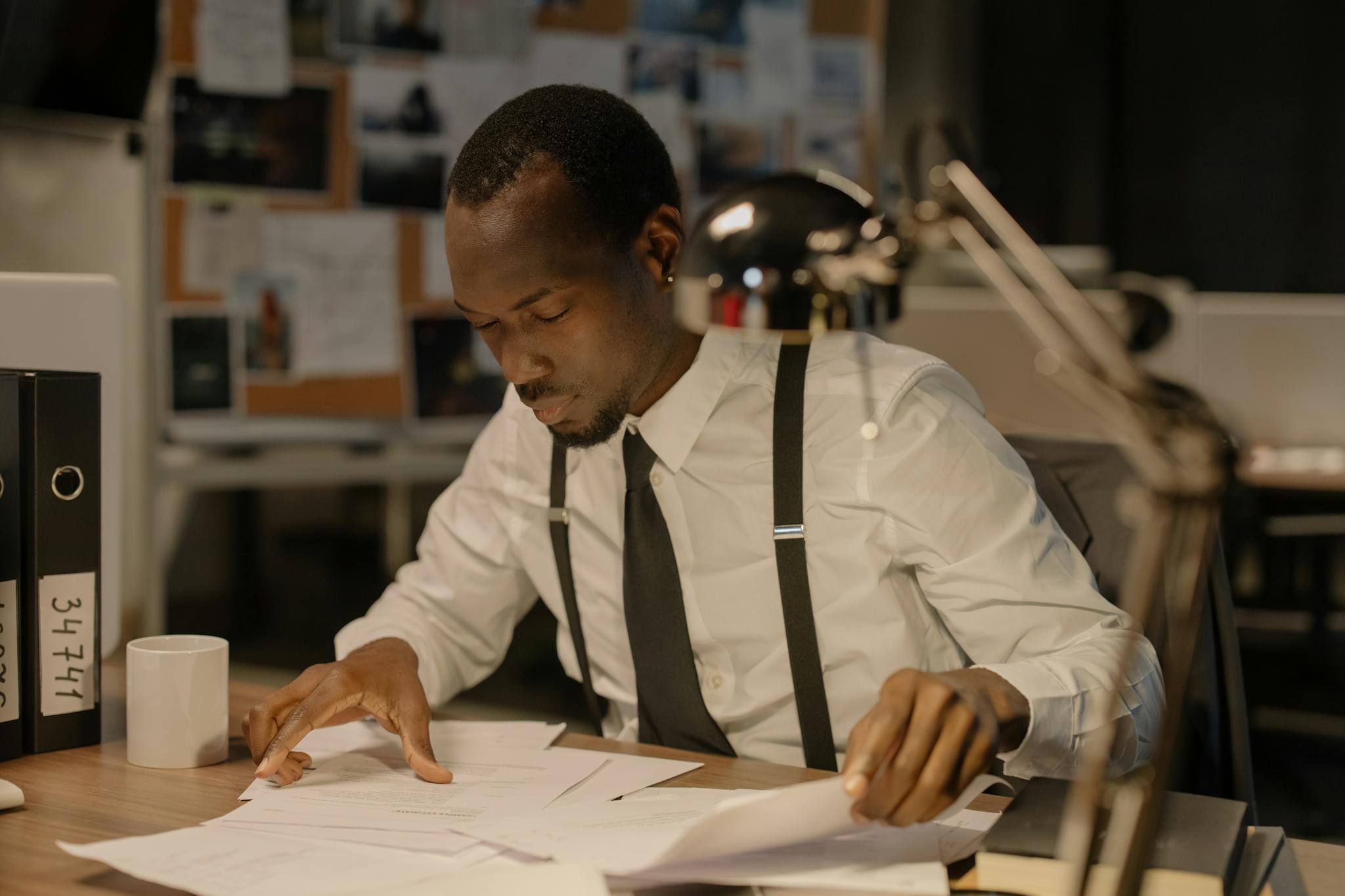 Detective concentrating on documents at desk, solving complex cases in office setting.